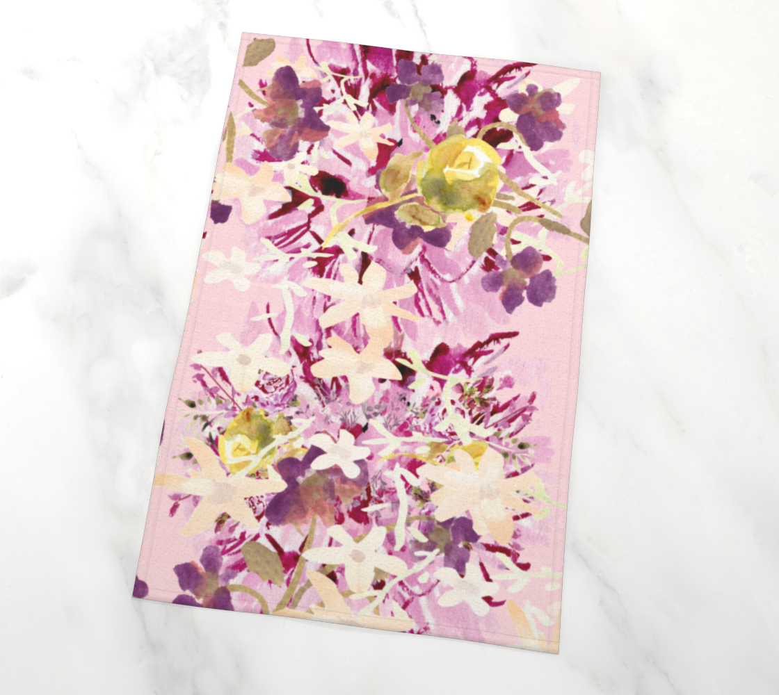 A tea towel with a light lavender background. The towel is covered with a dynamic scattering of hand-painted flowers in white, yellow, purple, with accents of green depicting leaves and stems