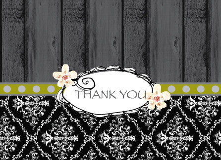 Top half of the card's background is a grey-toned repeating wood panel. Slightly off center, a light green line with large white dots serves as a thin border. Below, a black and white lacy pattern completes the bottom of the horizontal card. In the center a white oval with black squiggly semi circles surround the oval. Two white flowers are hand drawn to look like daffodils. The words Thank You is centered in the oval in a black font