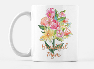 white ceramic mug with a bouquet of hand painted flowers in red, pink, orange, and yellow with green leaves and stems printed on the mug. Below the bouquet the words "Beautiful Mom" in a gold cursive font