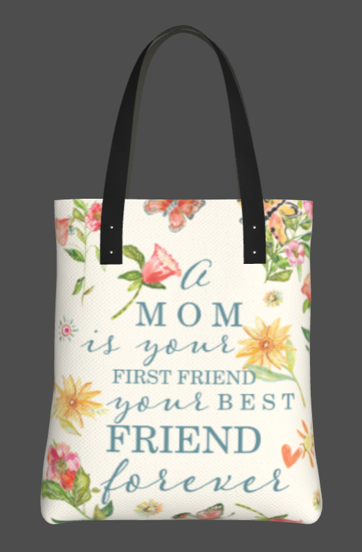 white cloth tote bag with various hand painted flowers in pink and yellow with green leaves. The words "A mom is your first friend your best friend forever" in a light blue font. The bad is adorned with a vegan leather strap shown in black